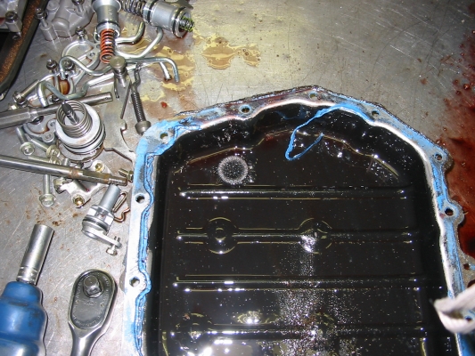 Oil pan with magnet, completely covered with shavings. OK here, but should be cleaned off more regularly, this magnet can't hold anymore. Parts to the left belong to a Toyota transmission which is orphaned from a broken case.
